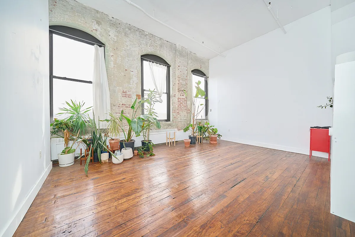 living space with wood floor, brick wall