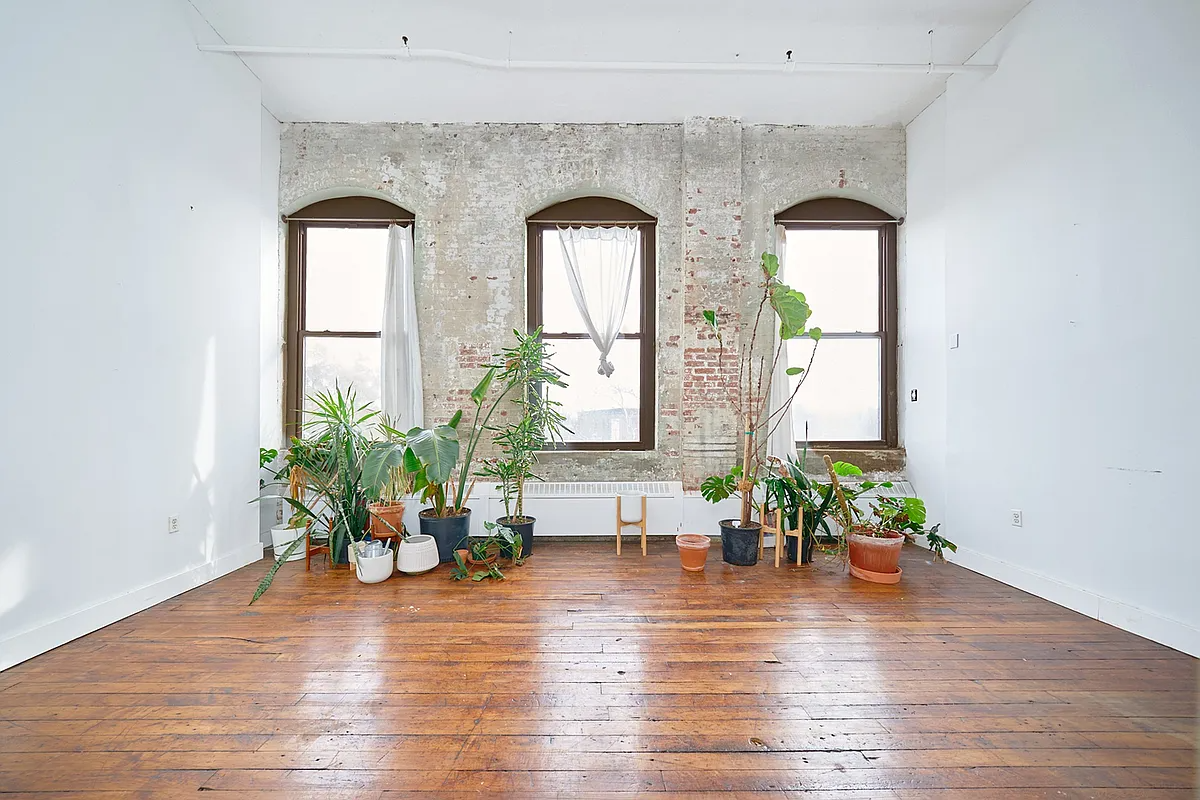 loft with three windows, wood floors, brick wall