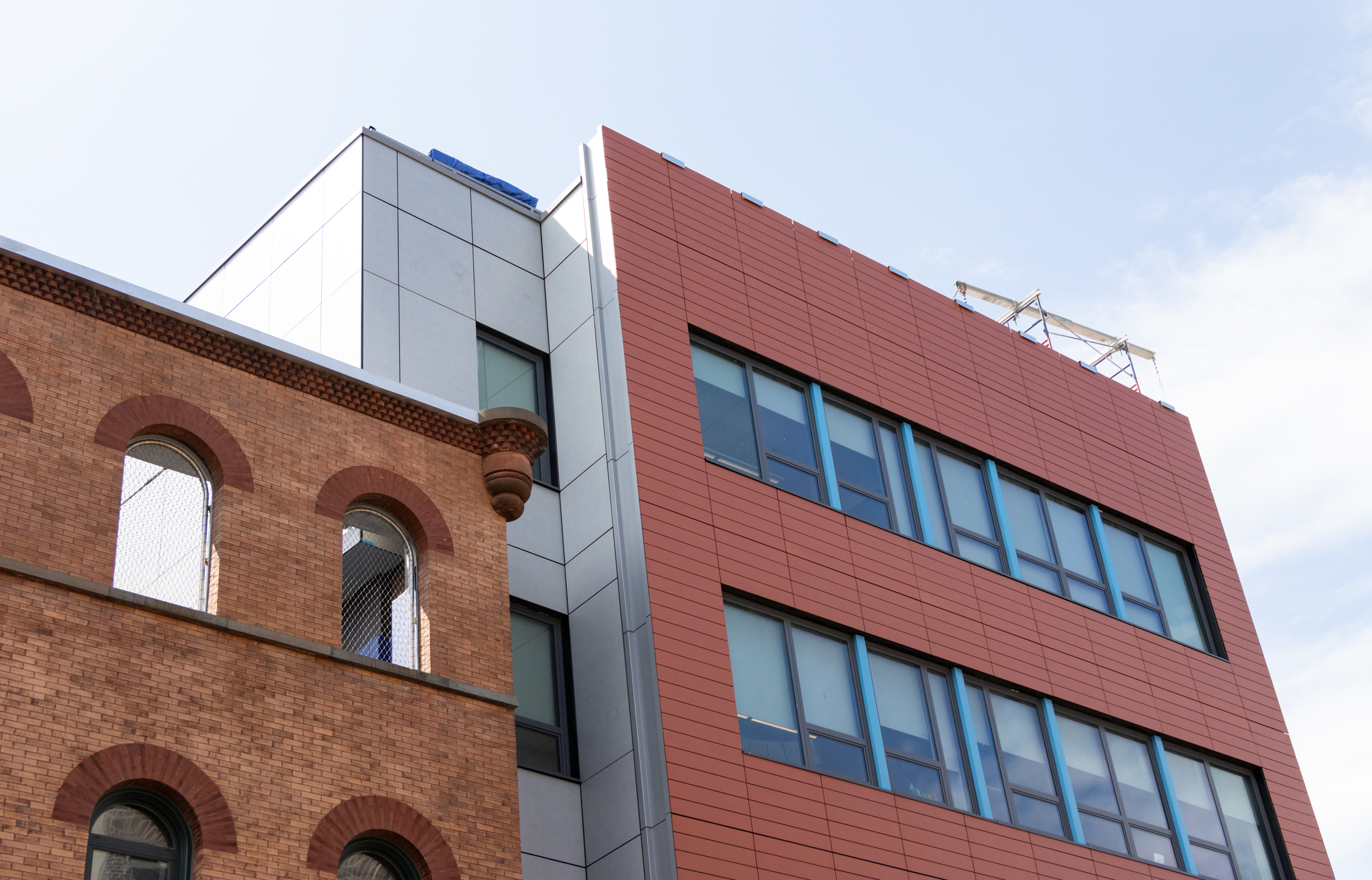 brick building and a new addition with red siding
