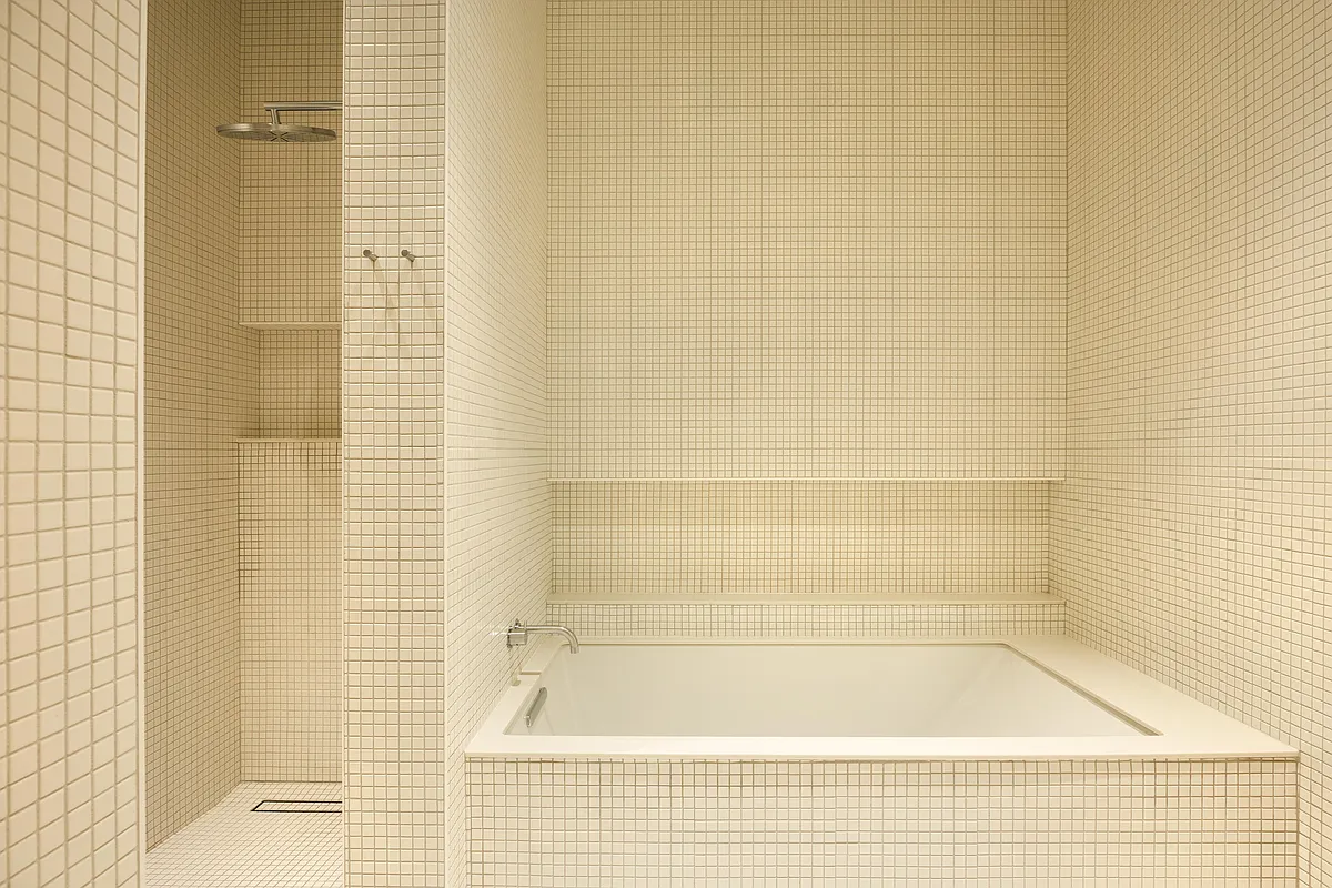bathroom with built-in shower with walls covered in cream mosaic tiles