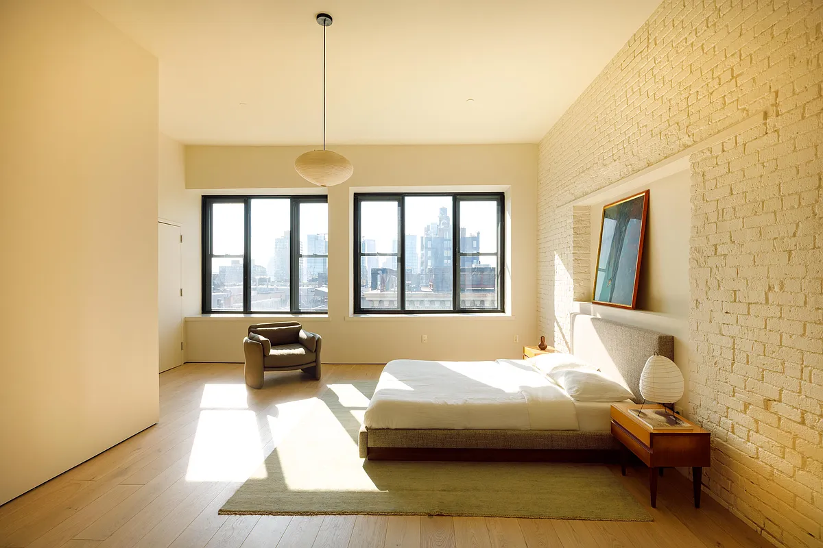 bedroom with one wall of exposed brick and all walls painted cream