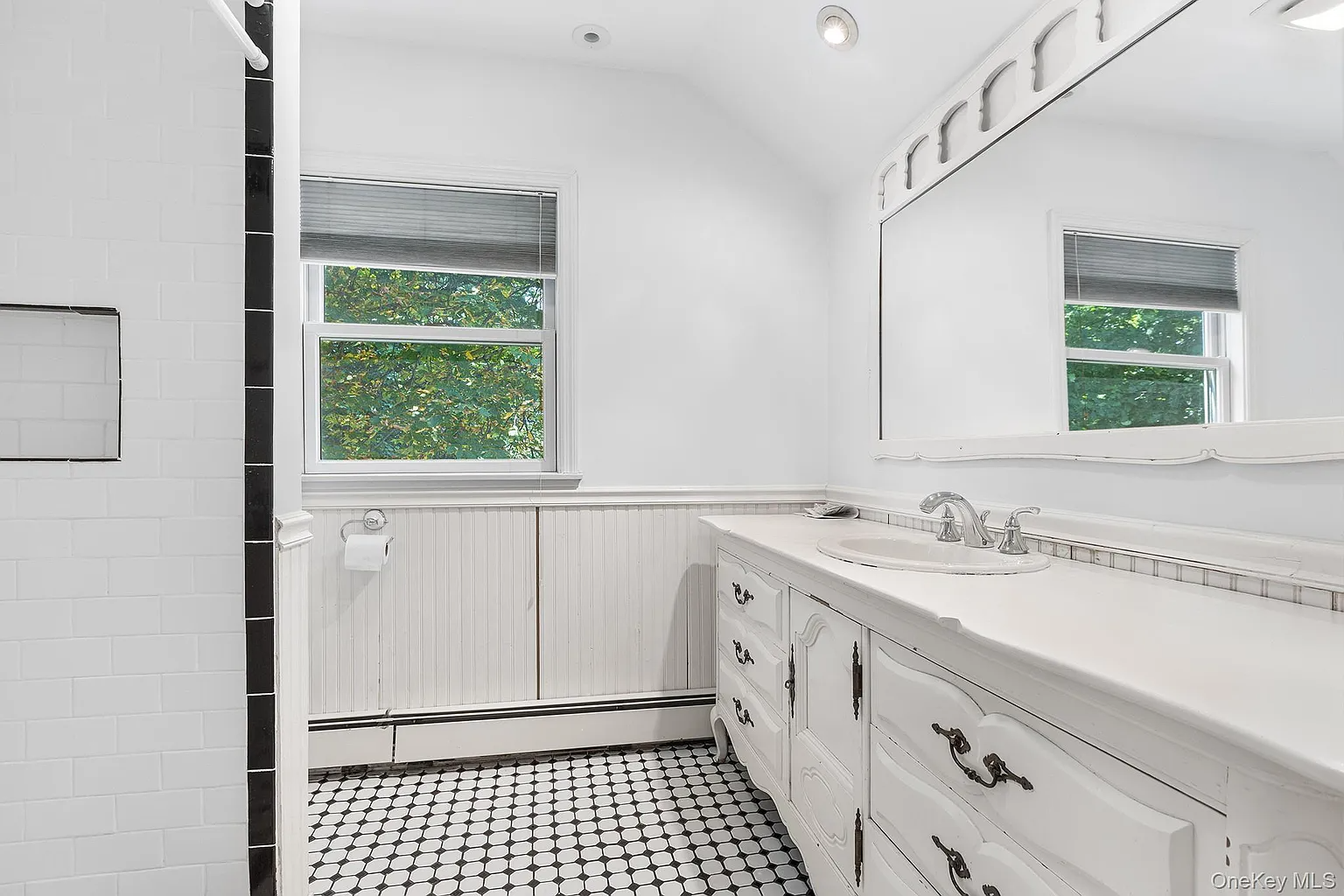 bedroom with beadboard, black and white floortile and a white vanity