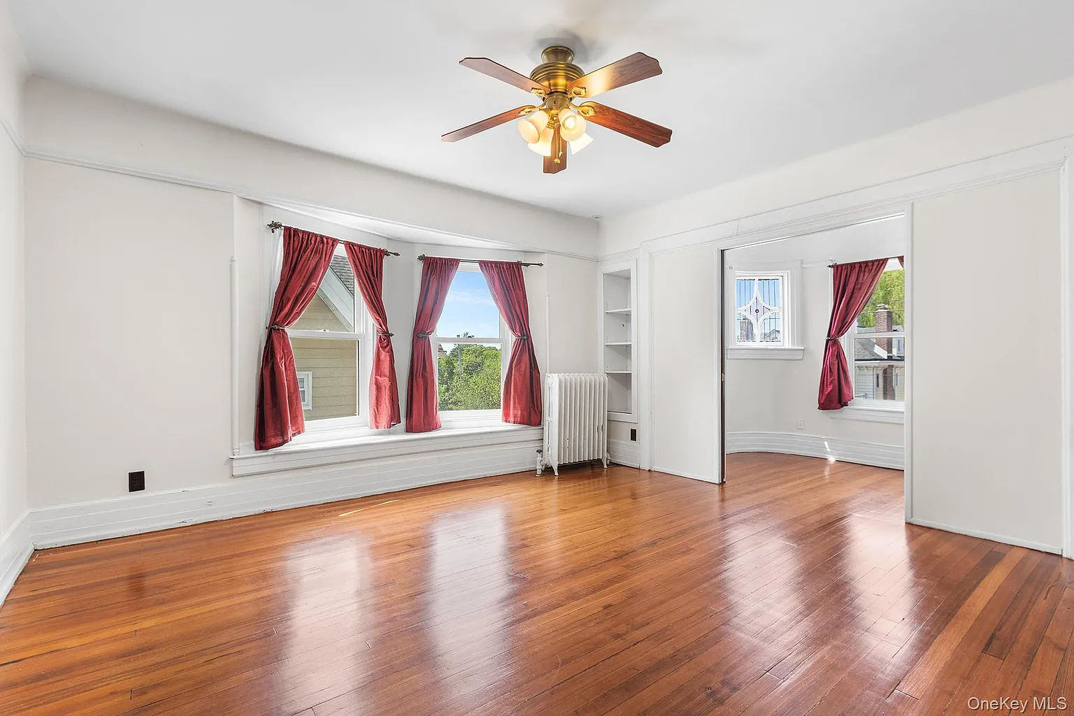 bedroom with window seat, ceiling fan and view into another room