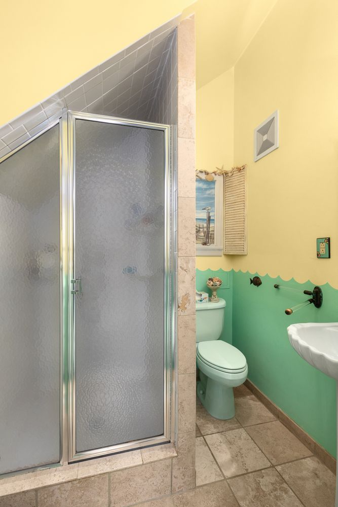 bathroom with shower, mint green toilet and green "waves" painted on the lower half of the wall