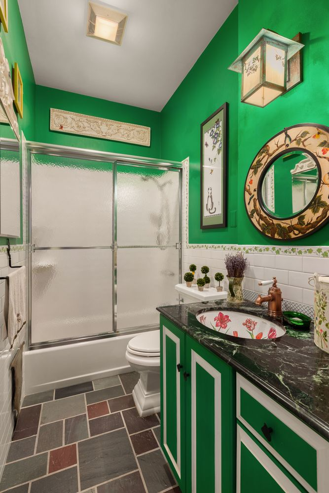 bathroom with green walls and cabinet, black marble counter, and floral sink
