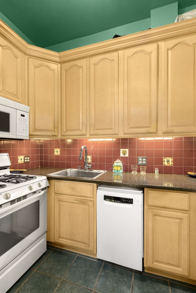 kitchen with terra cotta tile backspash, white appliances, light wood cabinets
