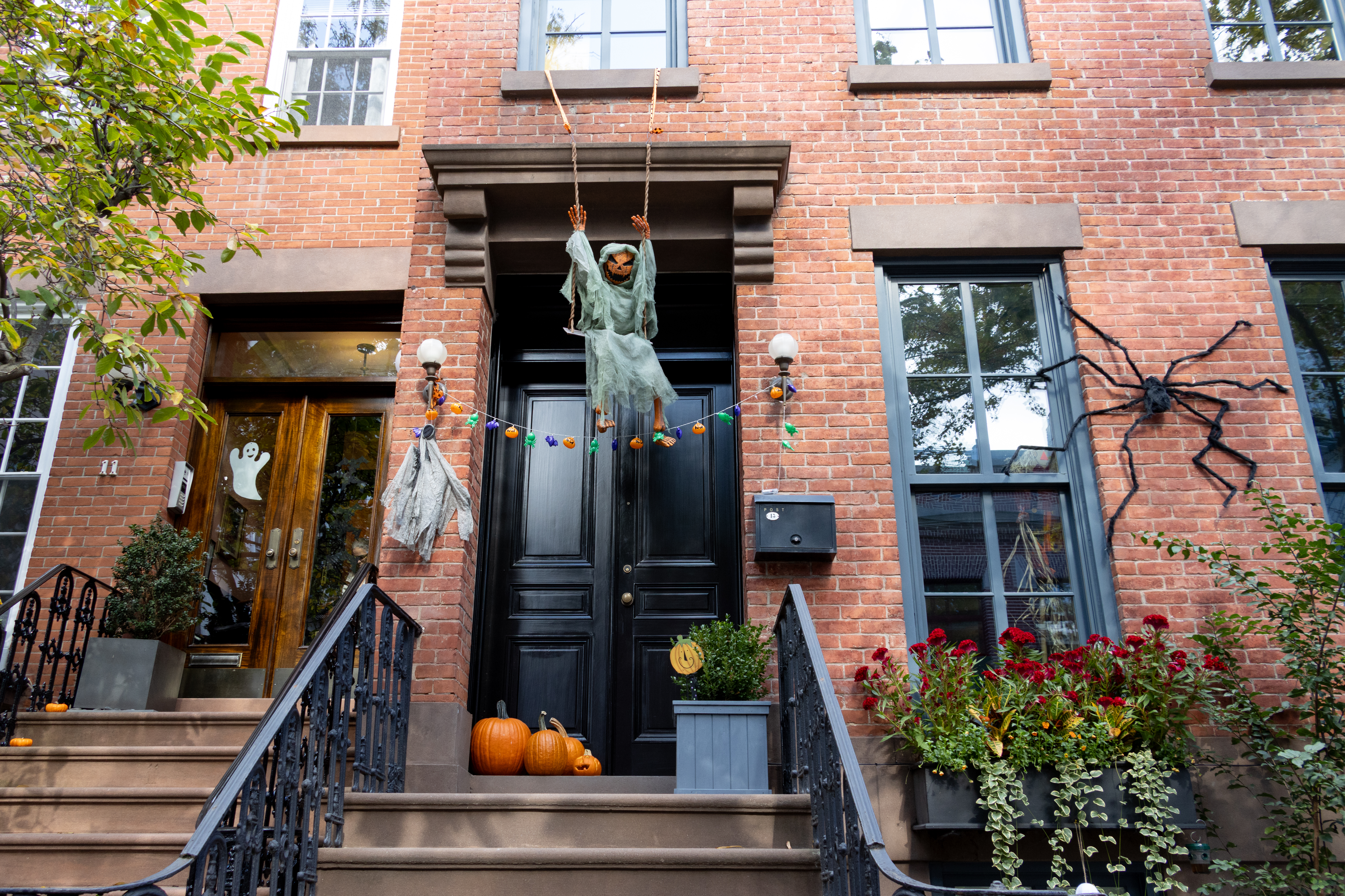 brick row house with halloween decorations including pumpkins on the stoop
