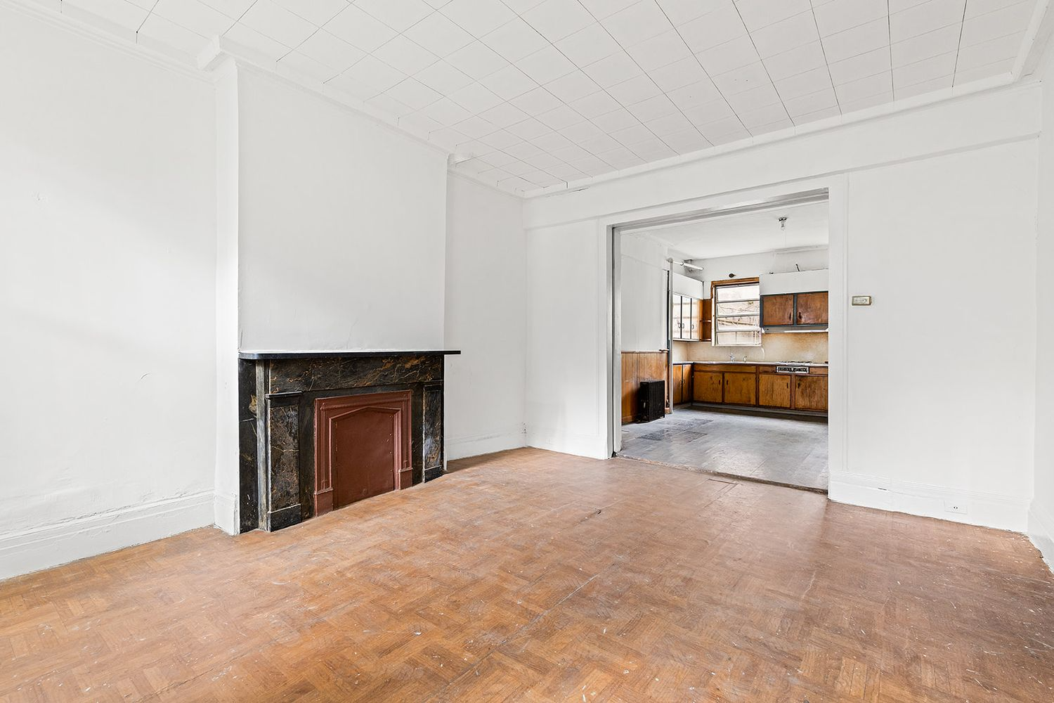 front parlor with black marble mantel and view into the kitchen in the rear parlor
