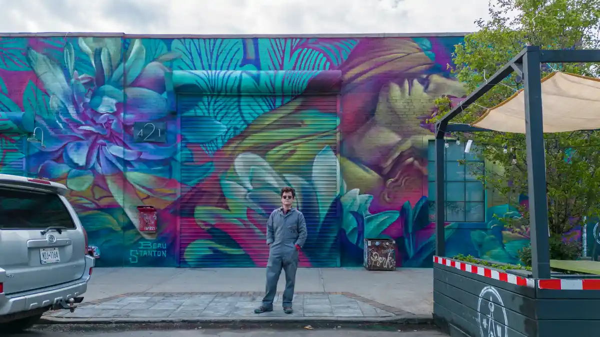 artist in front of a colorful mural