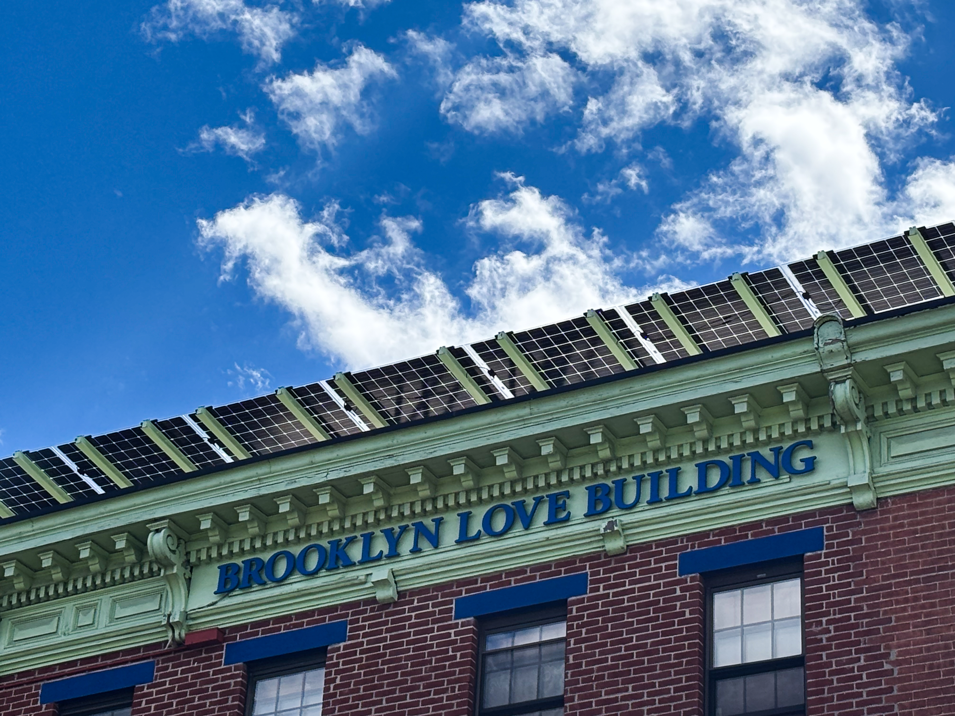 picture of the top of a roof with solar panels and blue skay and clouds 