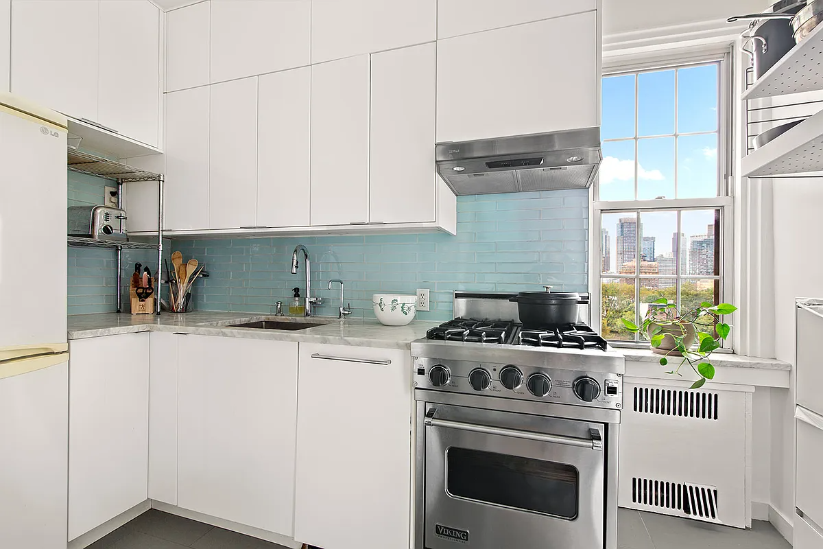 kitchen with white cabinets, blue backsplash and a tiny dishwasher