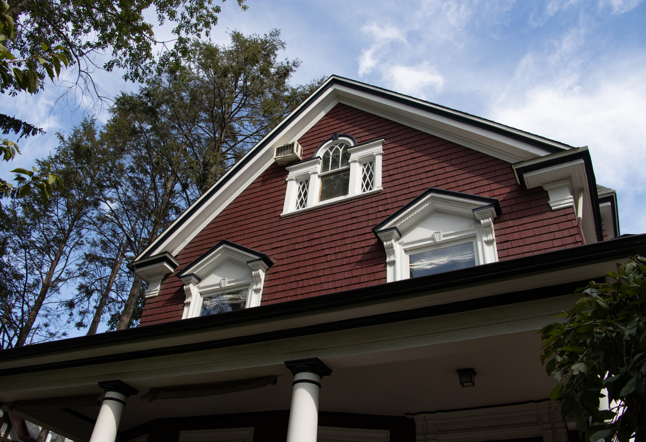 upper stories of a red sided house with some colonial revival details