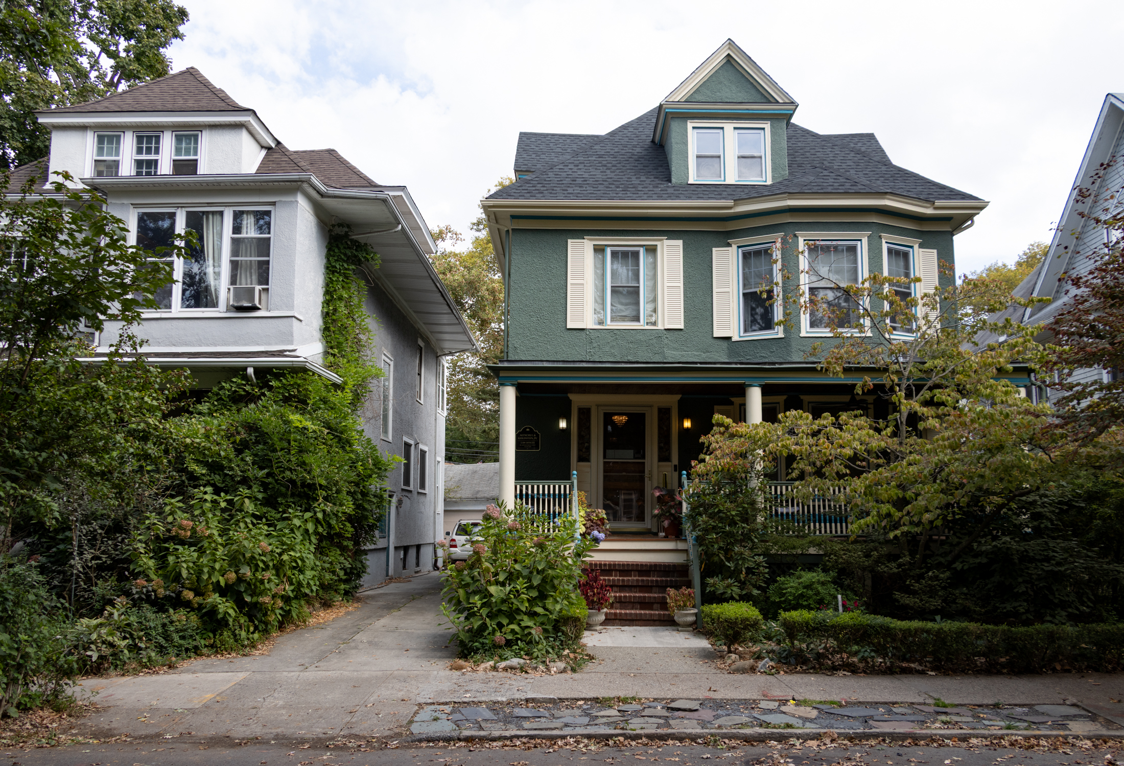 a house with a porch and a stucco upper story painted green