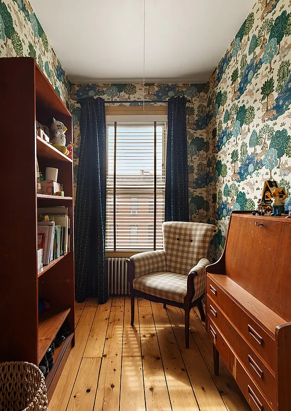narrow bedroom set up as a study with wallpaper with wooded scene
