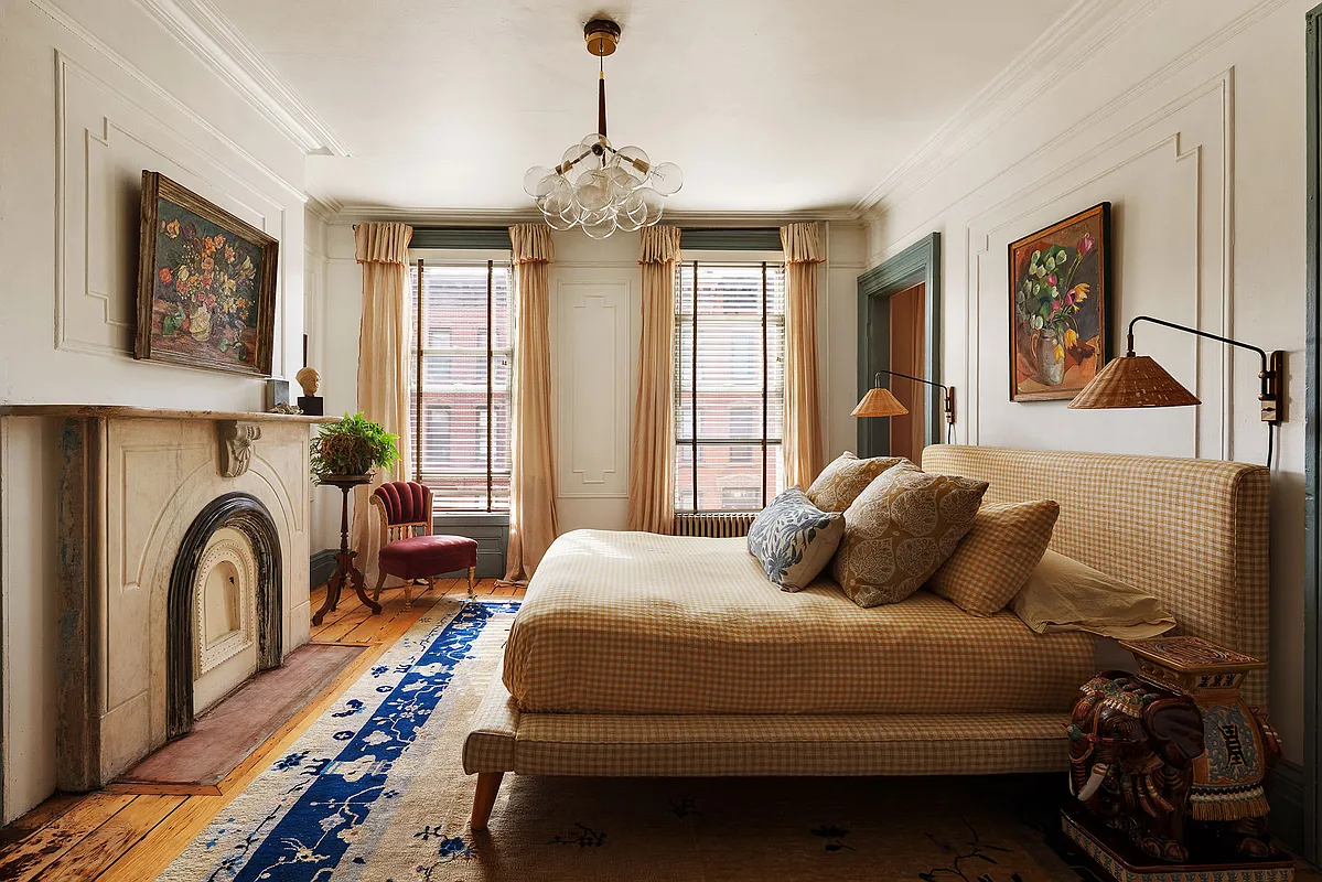 bedroom with wall moldings, marble mantel, wood floor