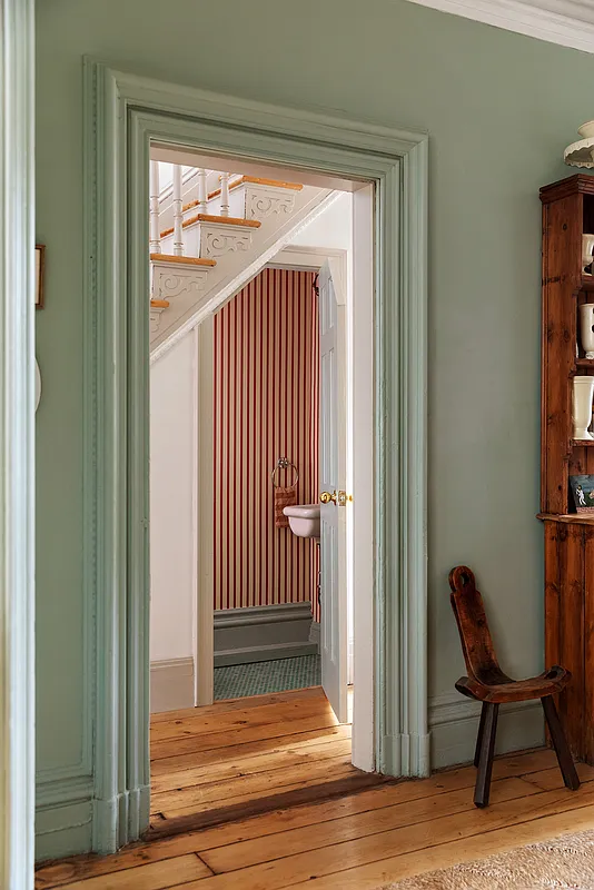view from dining to a powder room with red striped wallpaper