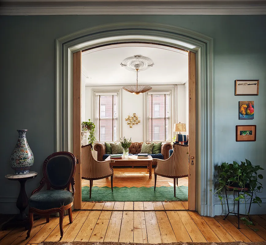 view through arched doorway with pocket doors in dining room with green walls to living room
