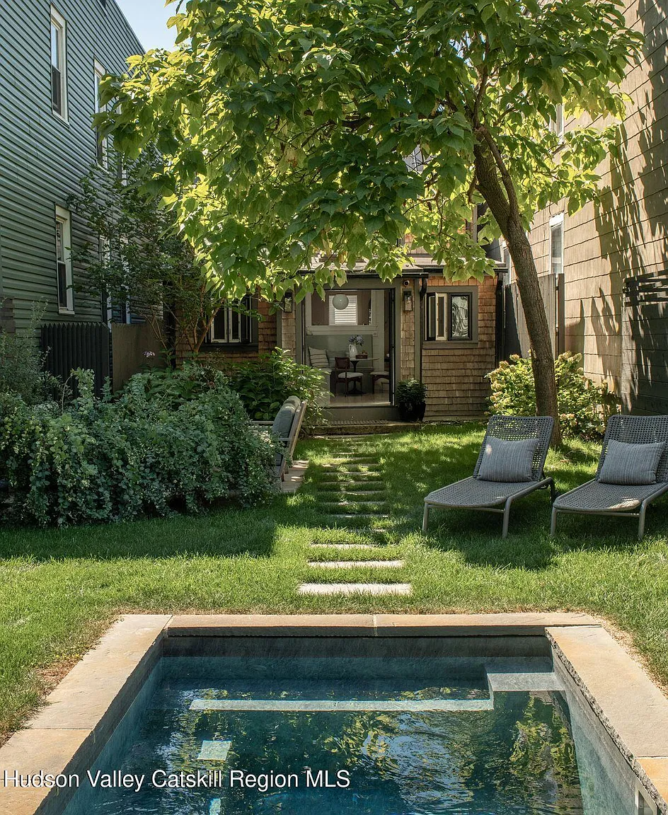 a rear yard with a narrow pool trimmed with stone