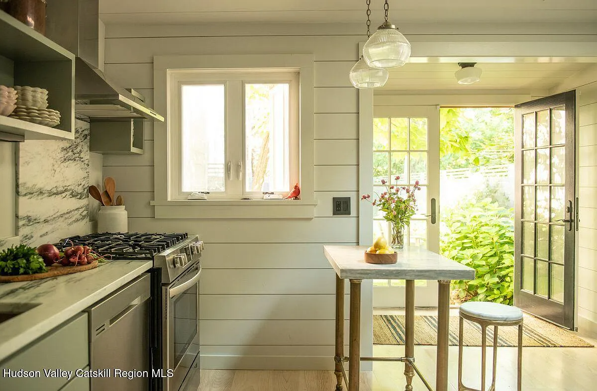 kitchen with shiplap on the walls, marble counters and room for a small table