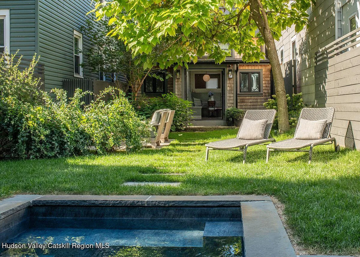rear yard with pool lined with stone and a view of the rear facade
