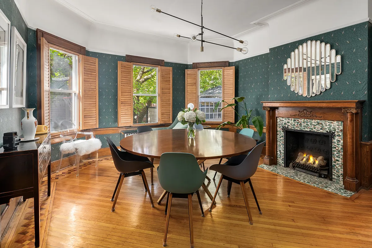 dining room with green wallpaper, wood mantel, wood floor
