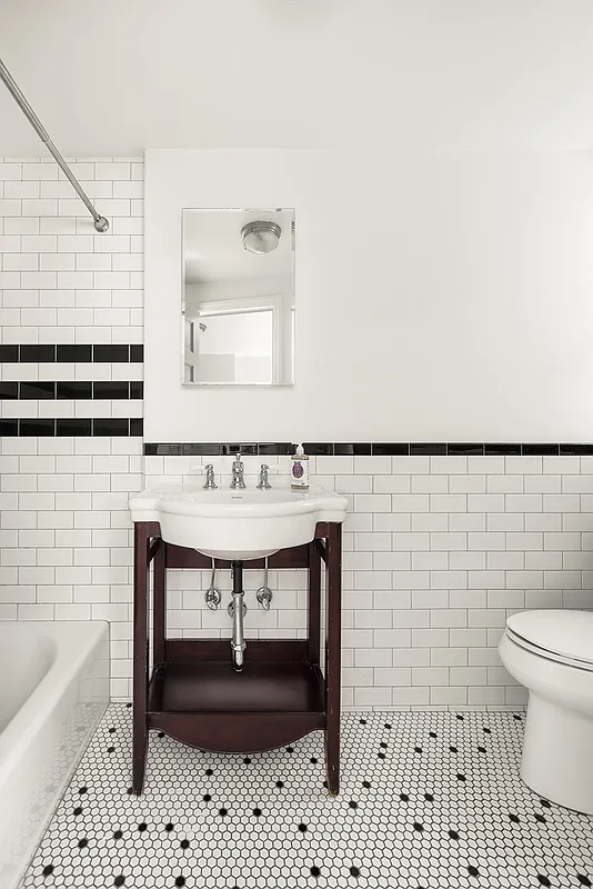 bathroom with white subway tile on wall with a black border