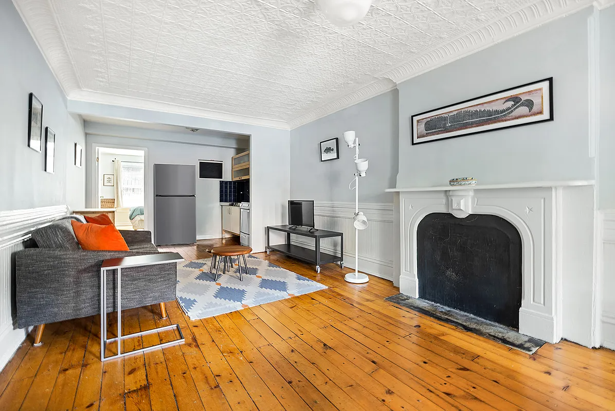 living room with wood floor, tin ceiling, marble mantel