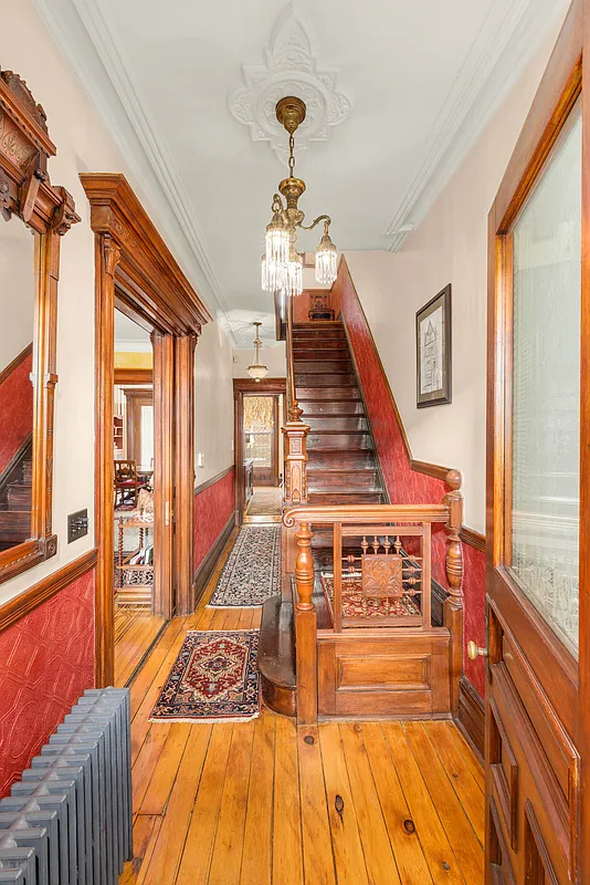entry hall with wood floor, original stair, and red lincrusta under the chair rail