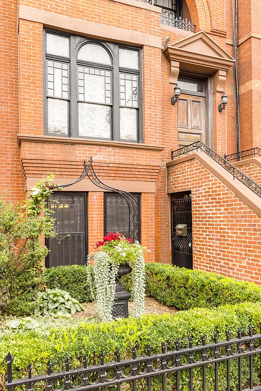 Garden with shrubbery in front of a brick row house