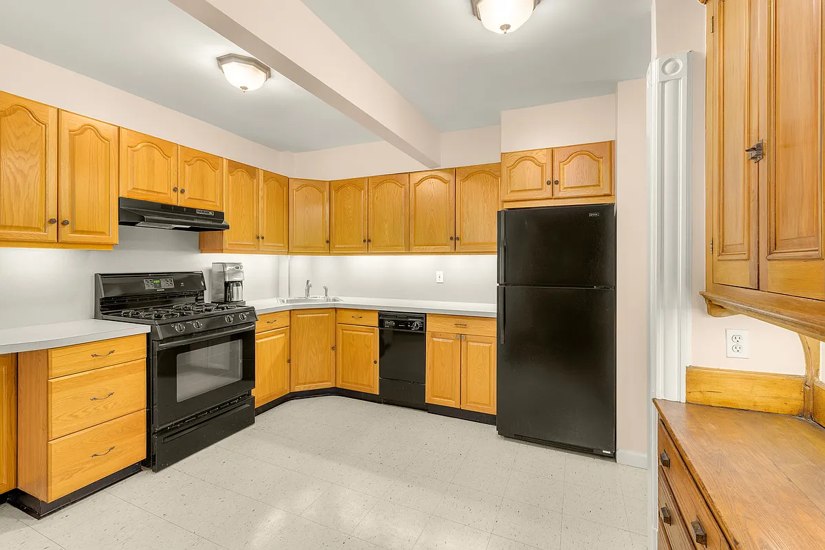 kitchen on garden level with light wood cabinets, black appliances including a dishwasher