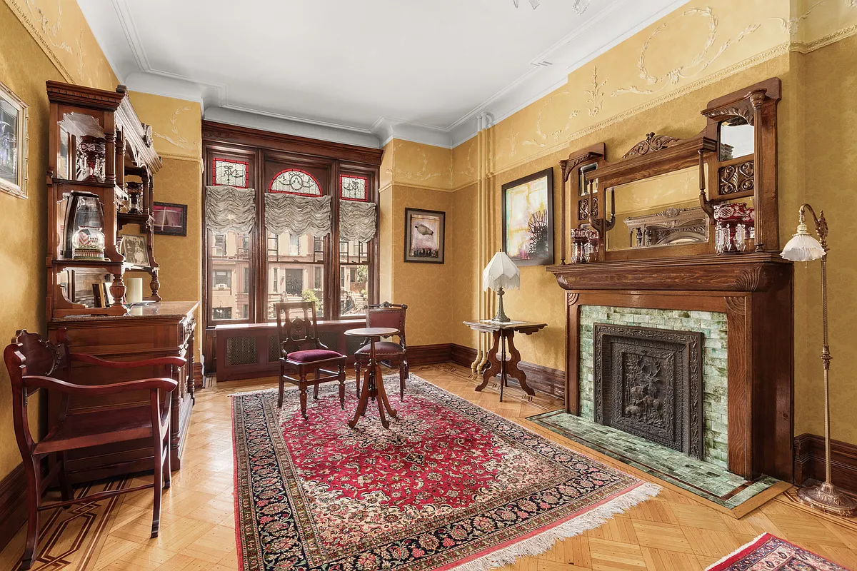 parlor with golden walls, plasterwork, wood floor and a wood mantel
