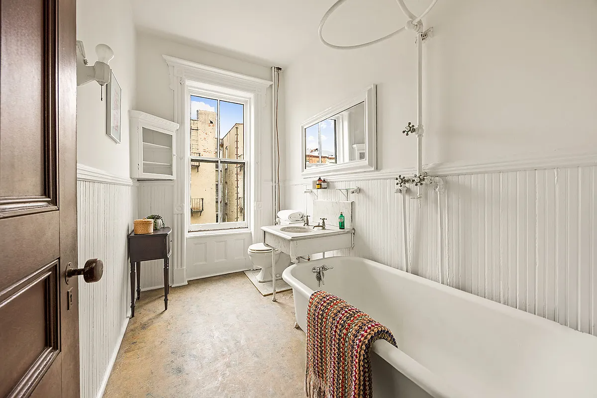 bathroom with beadboard painted white, claw foot tub, marble sink