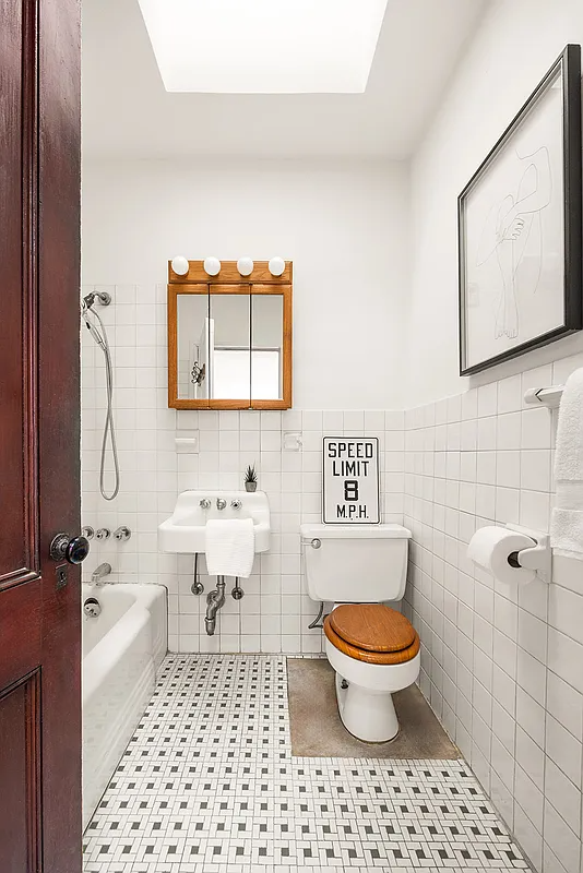 bathroom with white fixtures, skylight