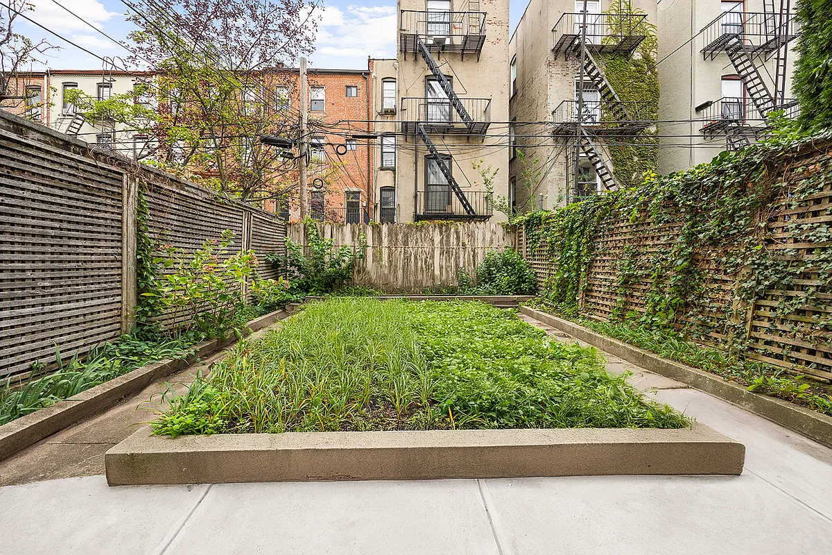 paved rear yard with planting beds on the sides and in the center