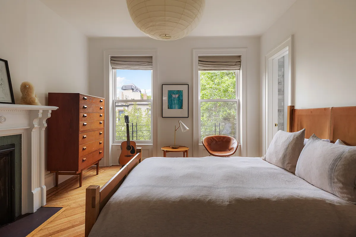 bedroom with white walls, two windows, white painted mantel