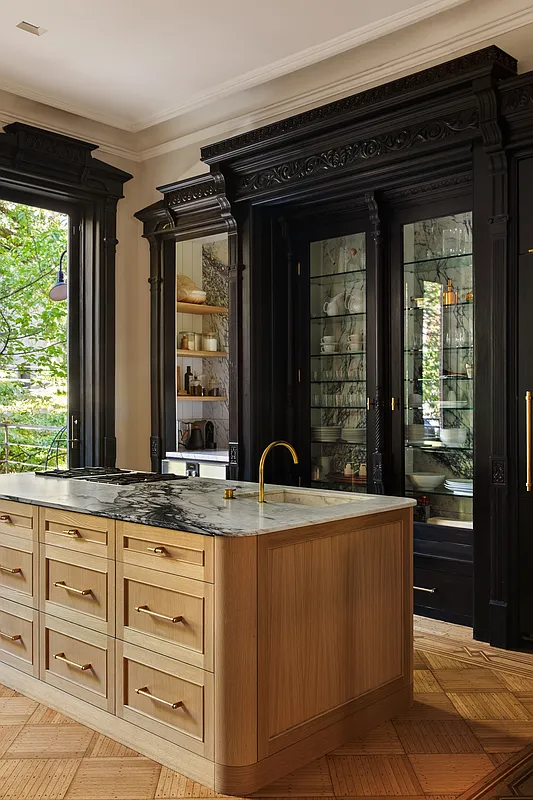 large marble topped island with sink and cooktop andoriginal-built-in behind