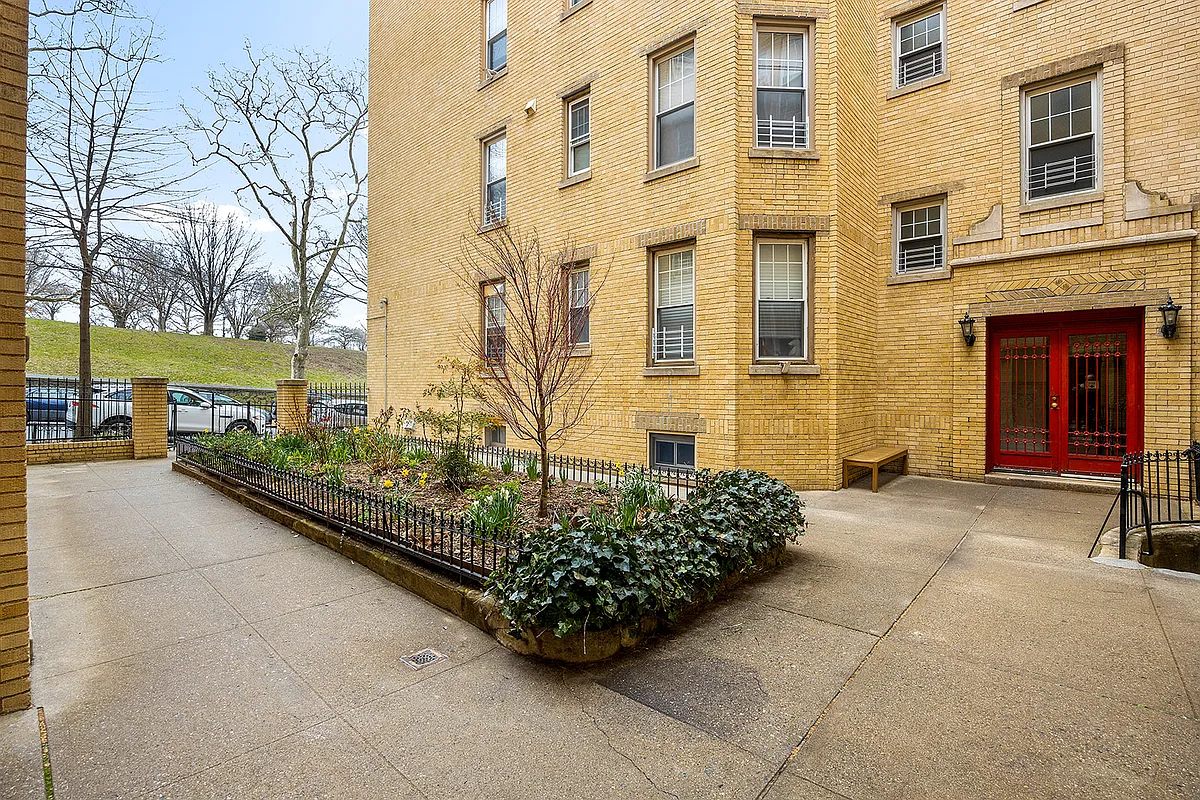 building exterior with yellow brick and a red door at the side entrance