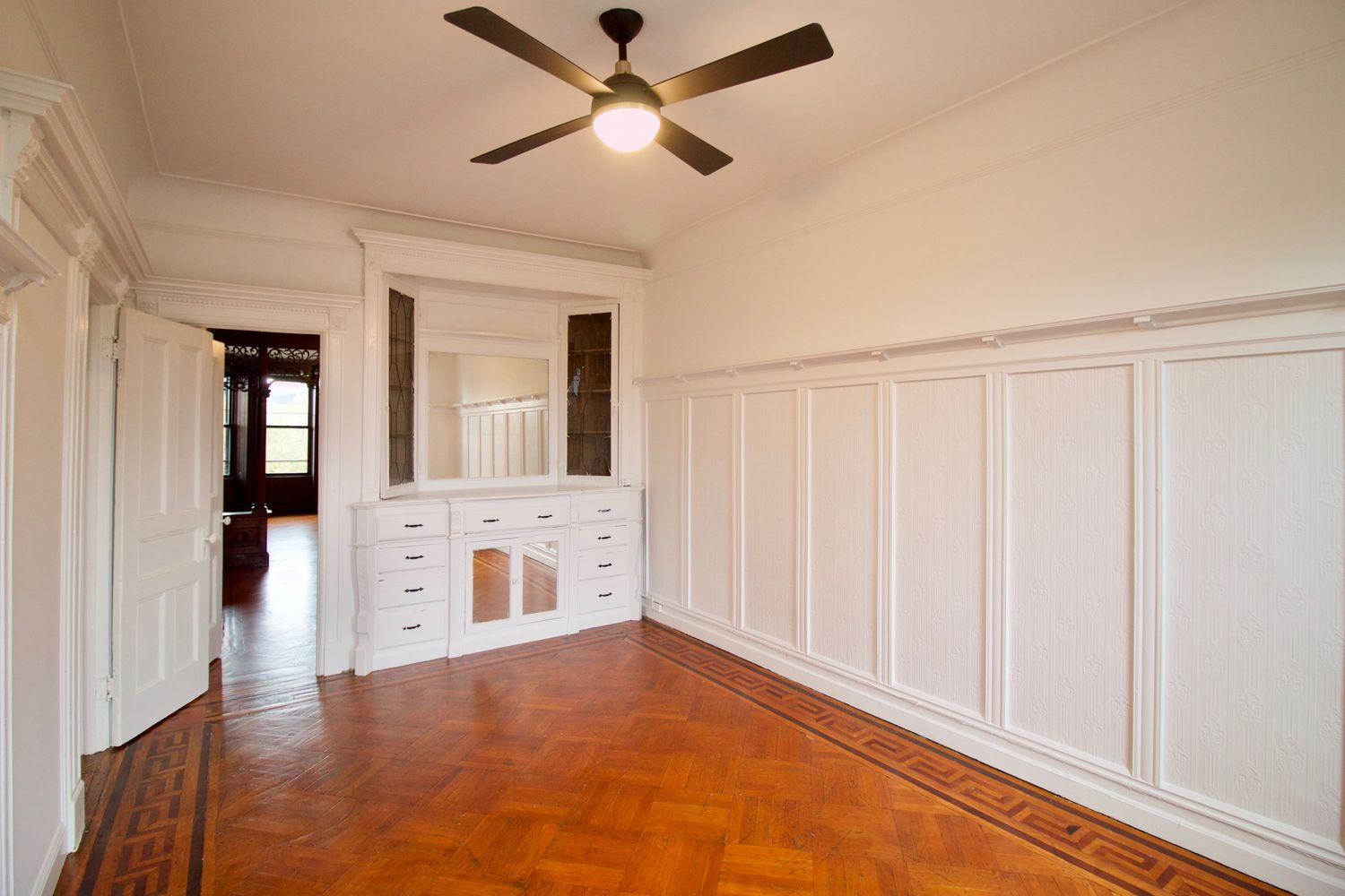 original dining room with wainscoting, plate shelf and wood floor and view into middle parlor
