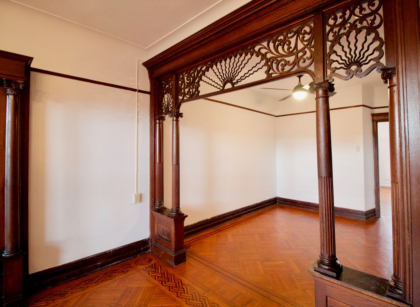 parlor with wood floor, pier mirror and fretwork screen framing entry to middle parlor