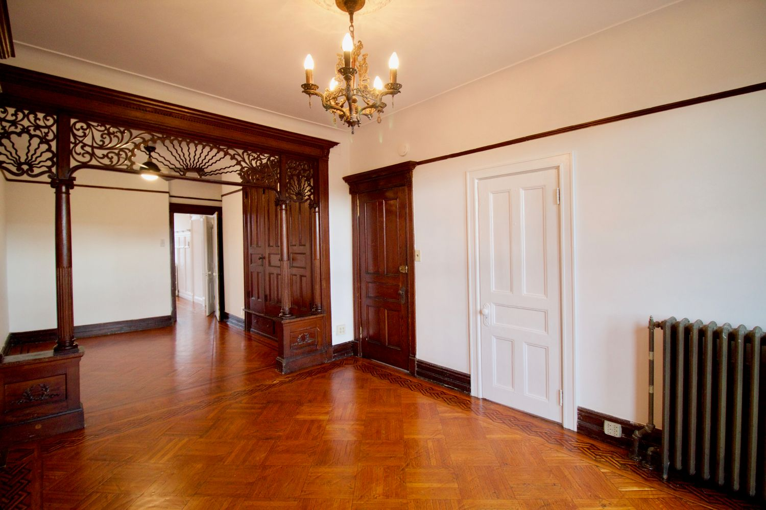 parlor with wood floor, pier mirror and fretwork screen framing entry to middle parlor