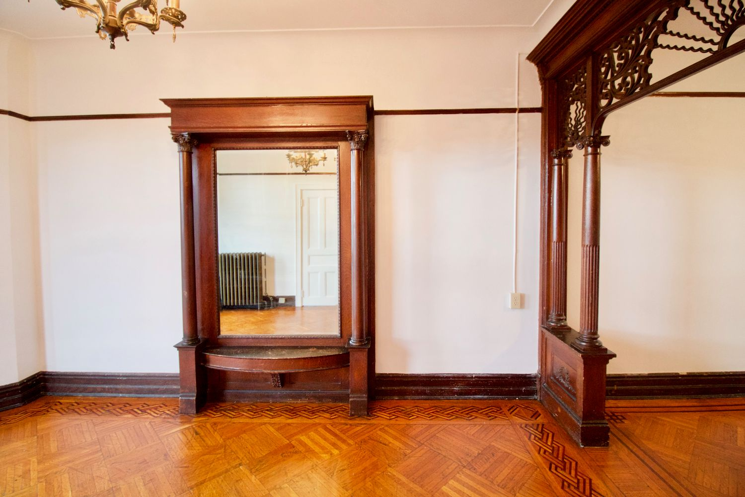 parlor with wood floor, pier mirror and fretwork screen framing entry to middle parlor