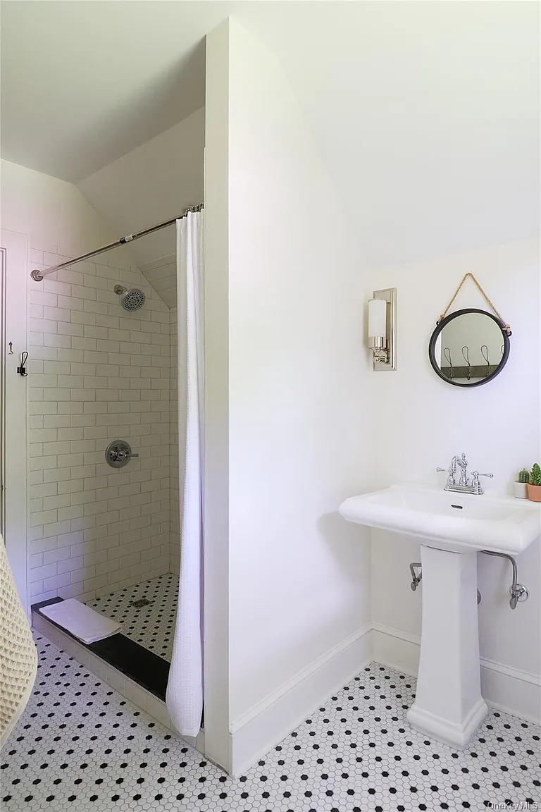 bathroom with black and white hex tile floor, walk-in shower, and pedestal sink