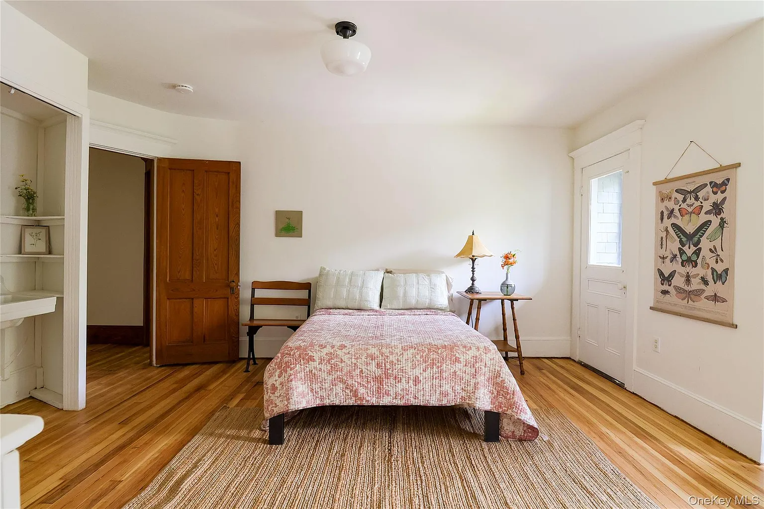 bedroom with wood floor, white walls, door with access to a screened-in balcony