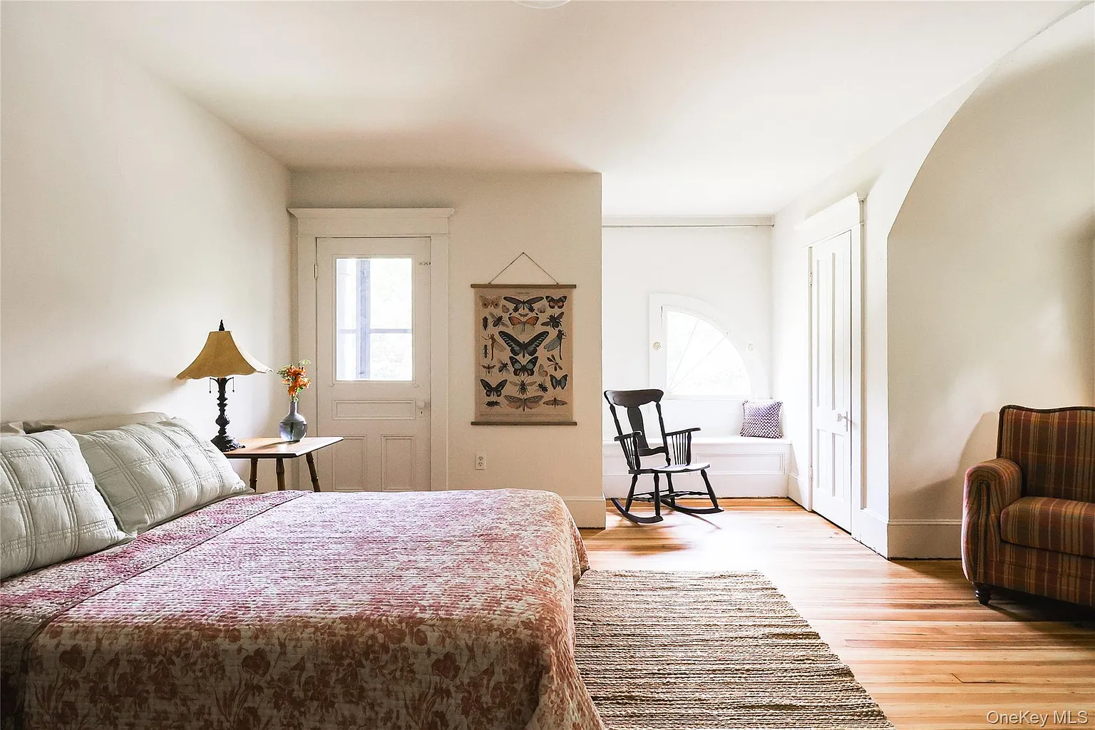 bedroom with wood floor, white walls, door with access to a screened-in balcony