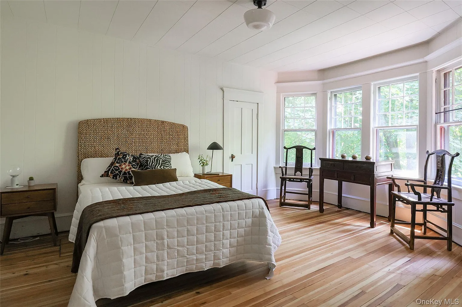 bedroom with wood floor, white walls, bay window