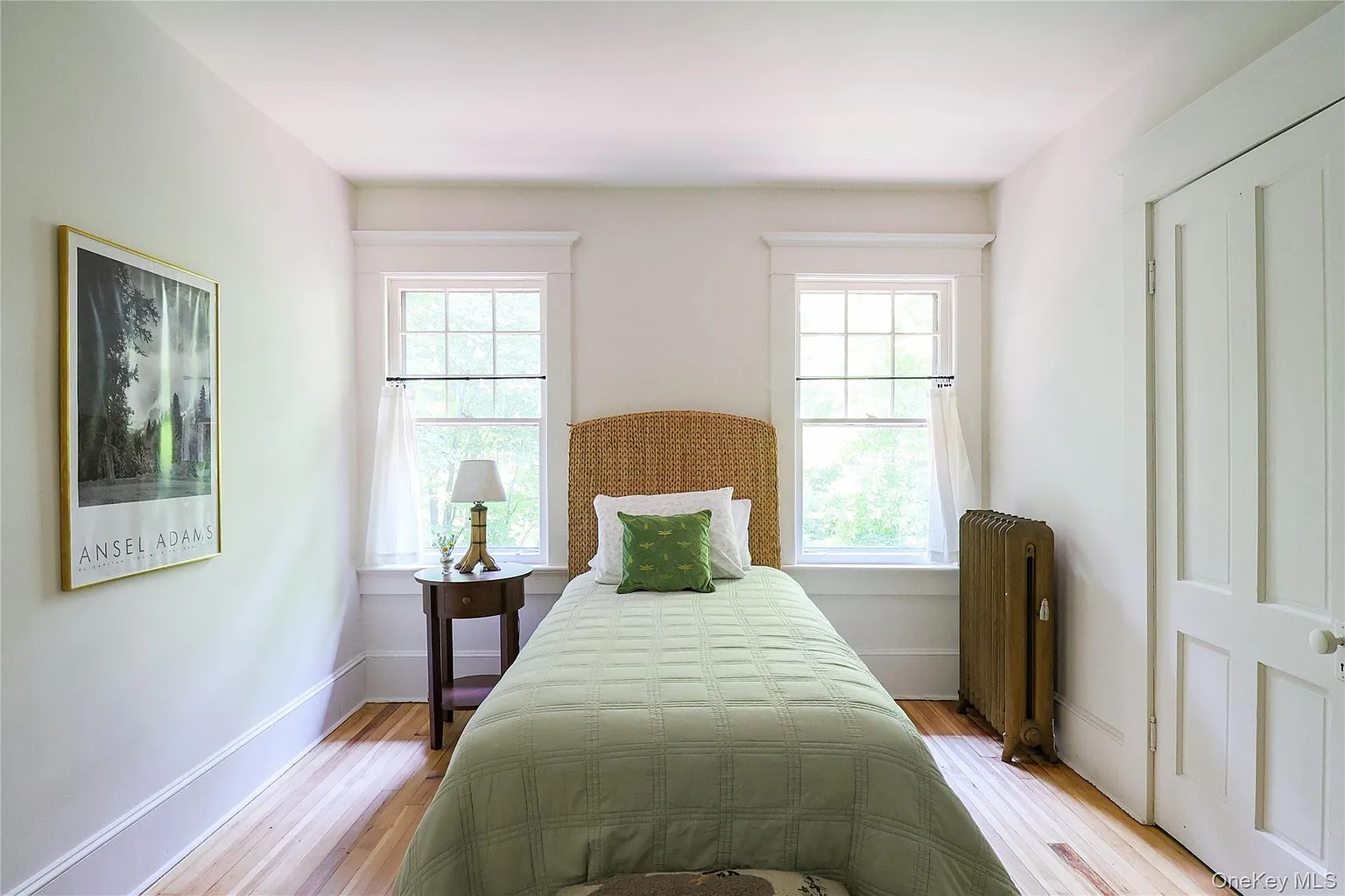 bedroom with wood floor, two windows, white walls