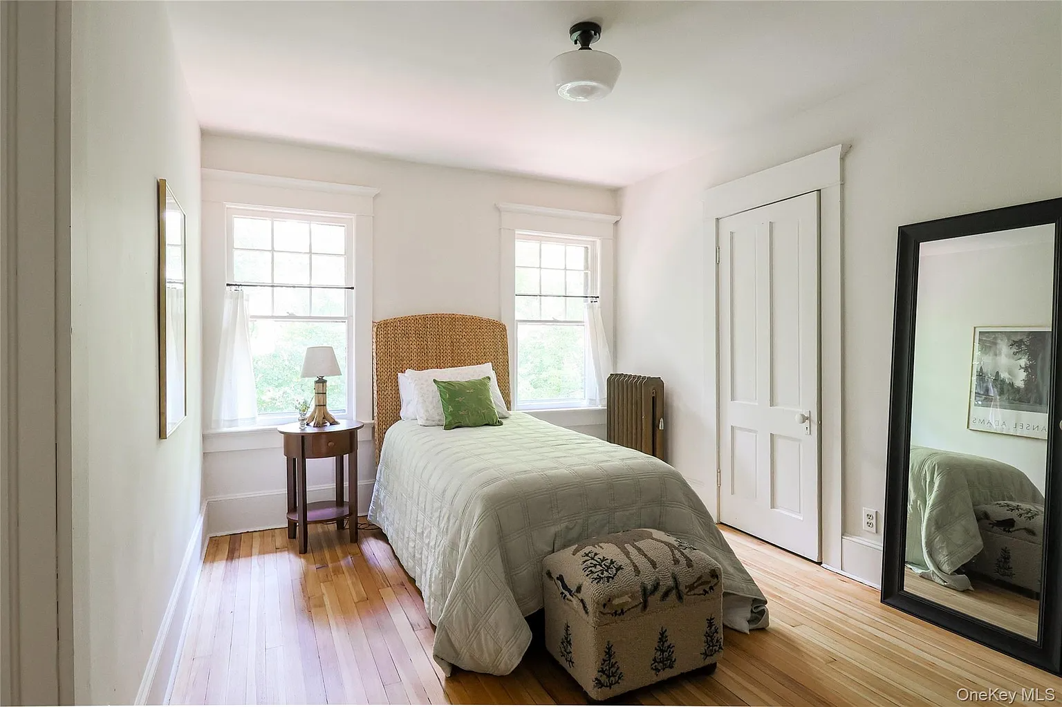 bedroom with wood floor, two windows, white walls