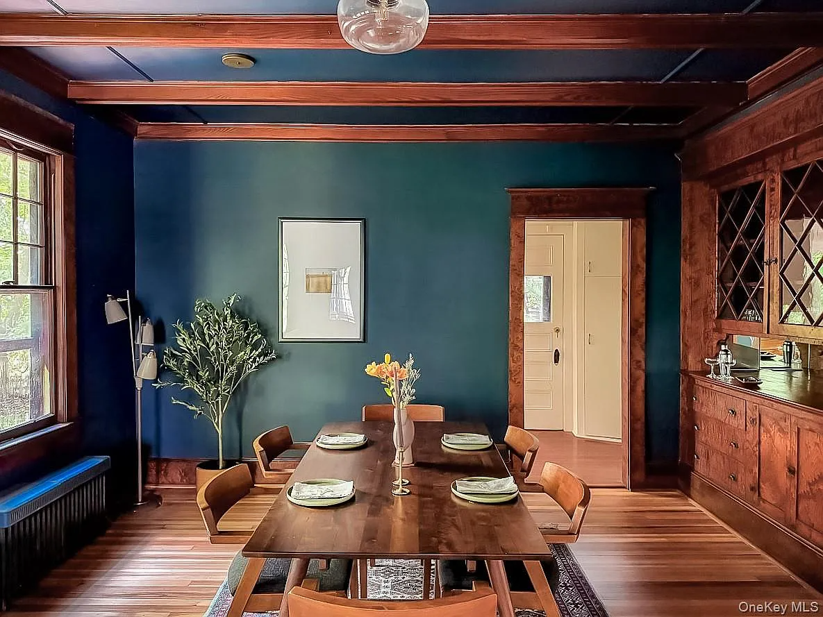 dining room with dark blue walls, beamed ceiling, built-in china cabinet