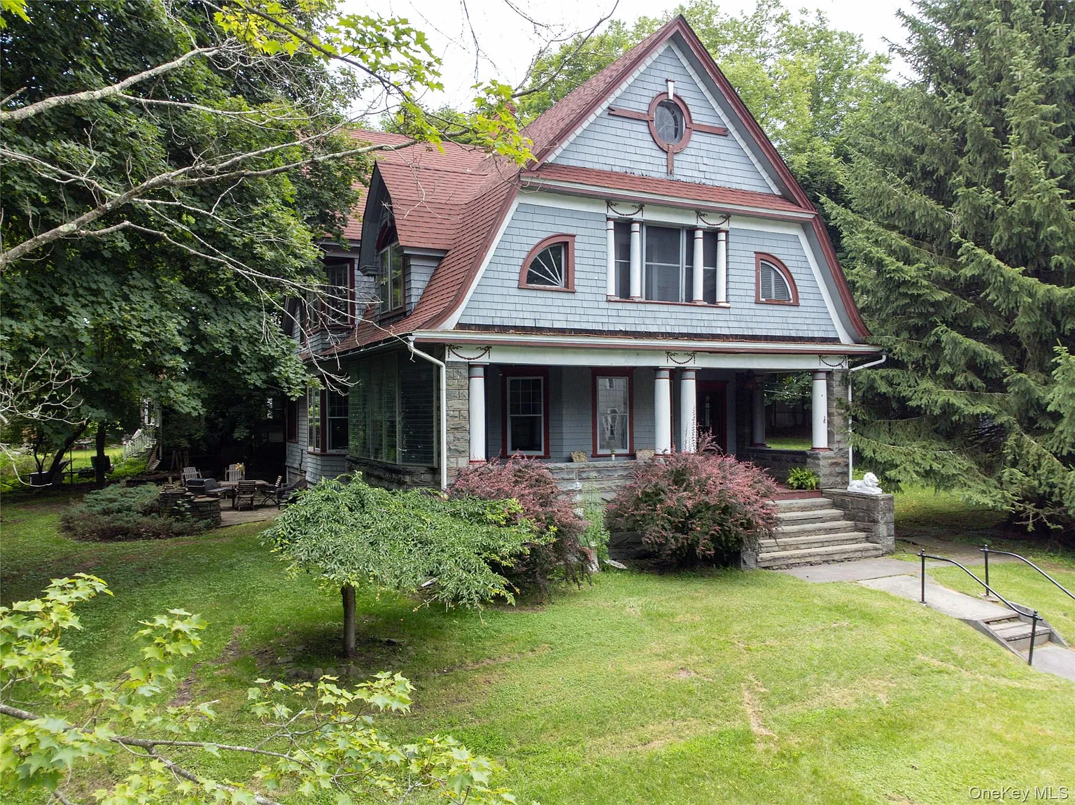 a shingle style house with blue shingles, red trim and a front porch