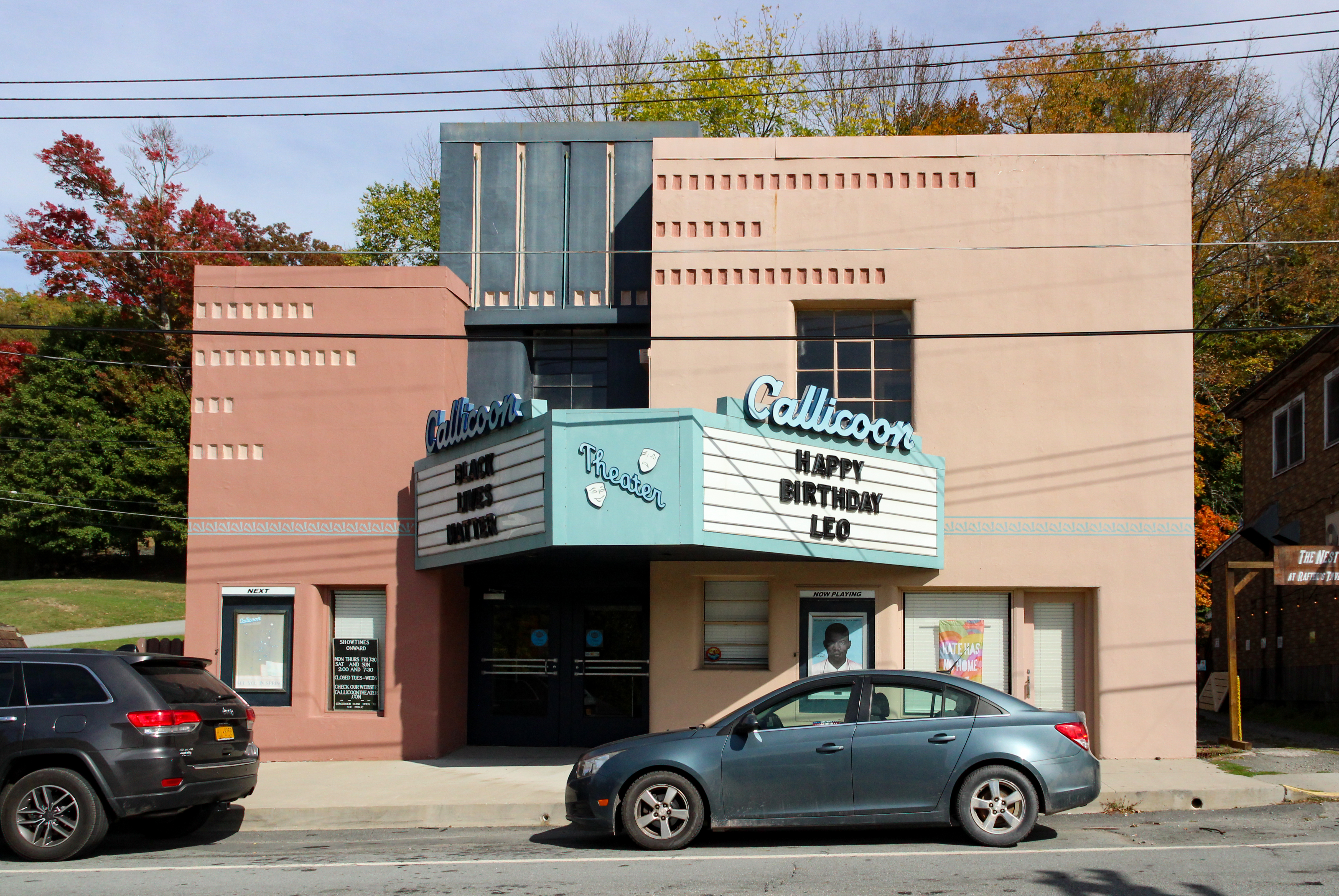 a pink painted art moderne movie theater with a marquee